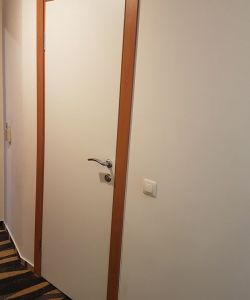 Белая гладкая пластиковая влагостойкая дверь Aquadoor с наличником в цвете миланский орех