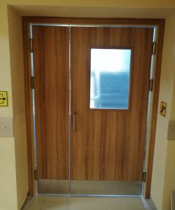 Композитные влагостойкие двери Aquadoor в с цвете песочный дуб в маятниковом исполнении с армированным стеклом и отбойной пластиной